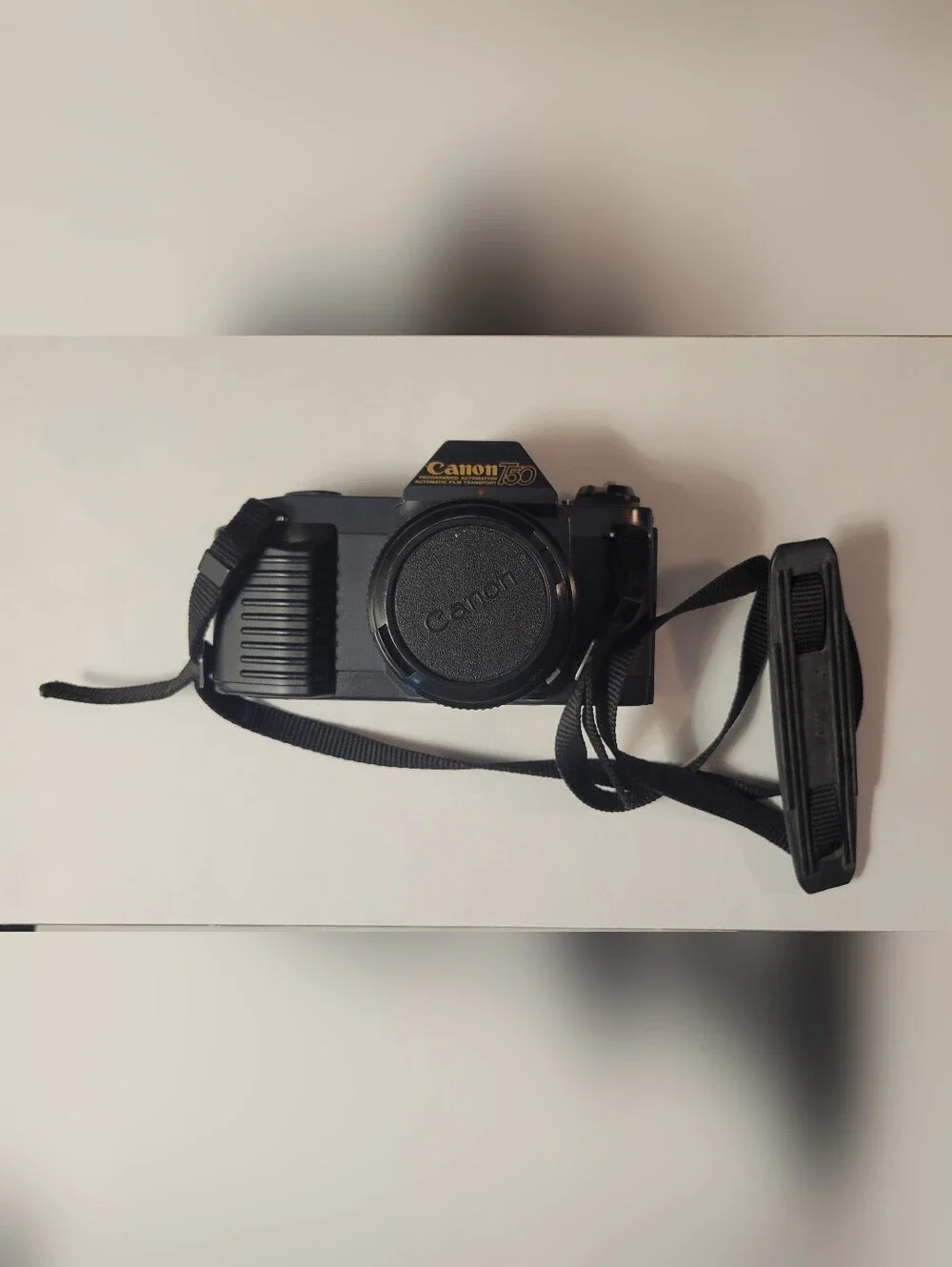 Canon black film camera with 50mm FD f/1.8 lens and neck strap